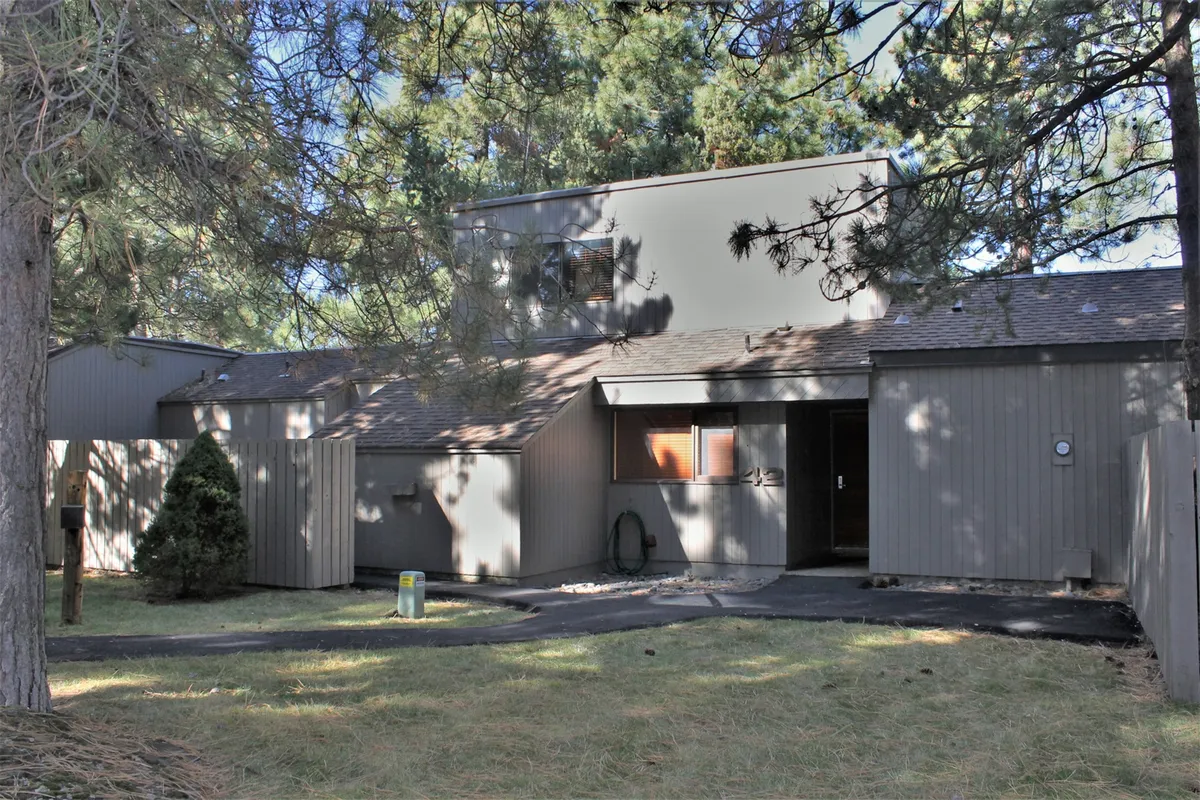 The exterior of the home showcases unique architectural design, surrounded by tall trees and inviting pathways leading to the entrance. The setting exudes a sense of tranquility and easy access to the outdoors.