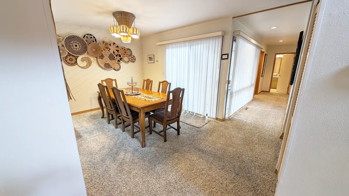 A spacious dining area featuring a large table, decorative wall art, and a modern chandelier. The table is set up to accommodate a group, making it ideal for shared meals and celebrations.