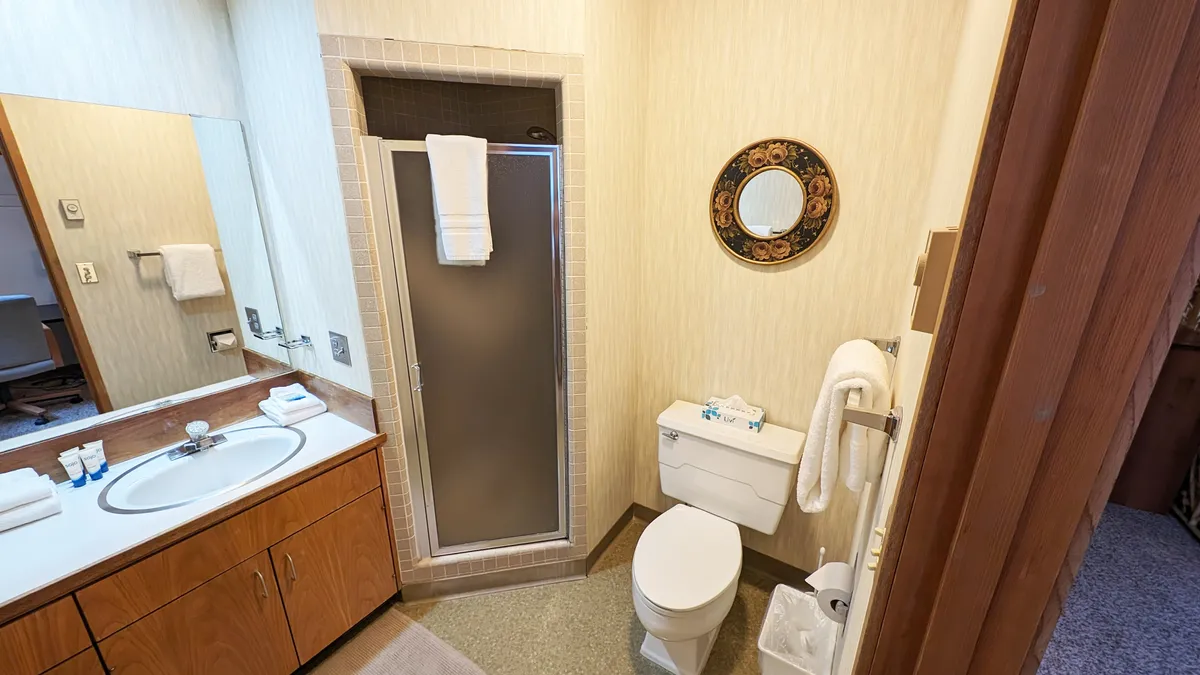 A compact, functional bathroom with a modern sink, walk-in shower, toilet, and fresh towels. The layout is practical, highlighting the convenience and privacy of an en-suite bath upstairs.